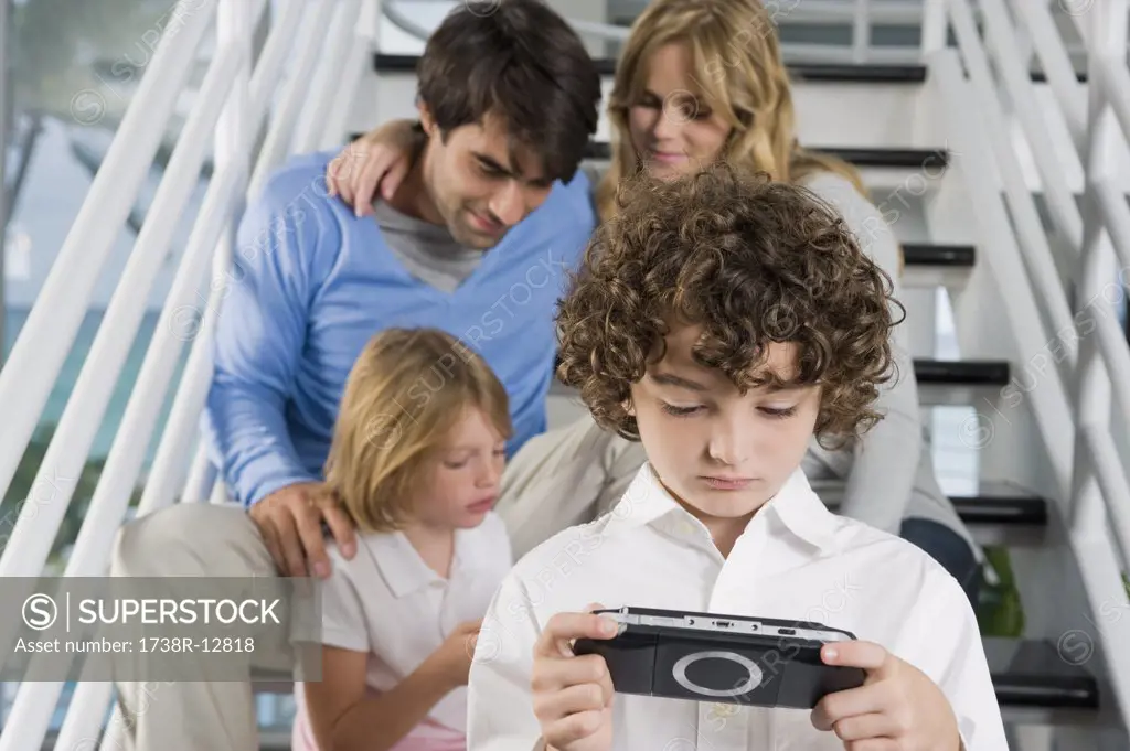 Parents sitting on steps with their children playing video games