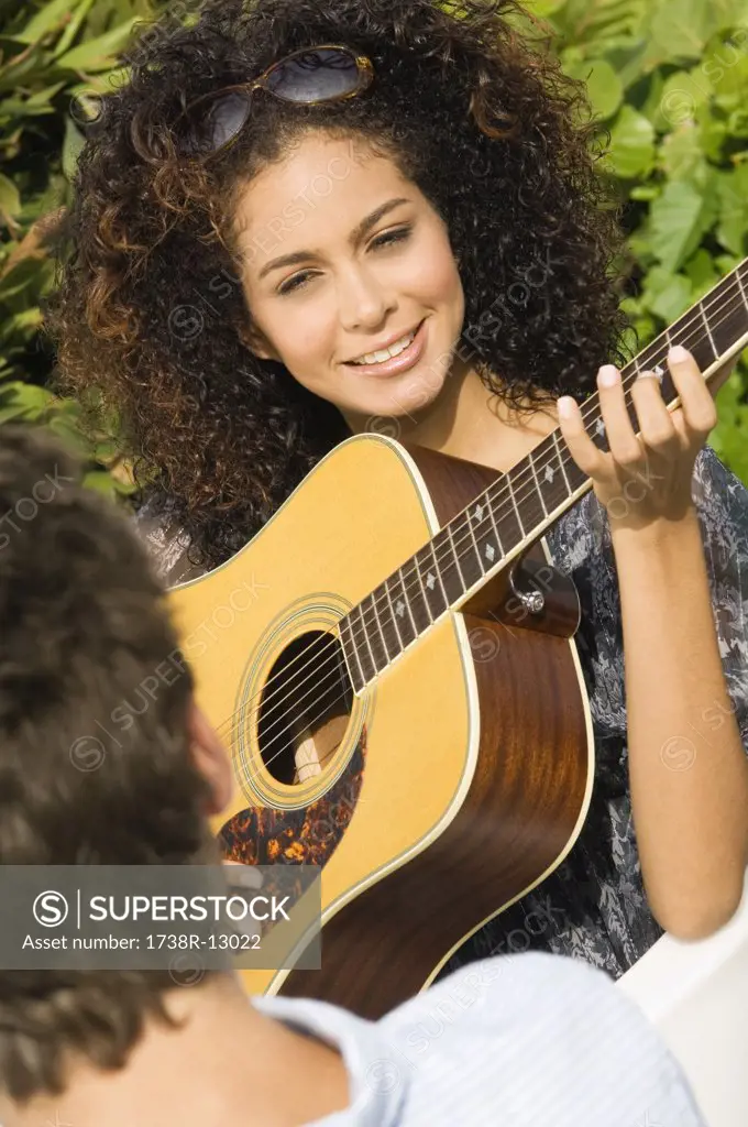 Woman playing a guitar in front of a man