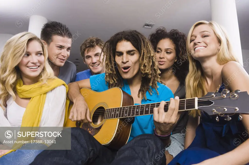 Man sitting with his friends and playing a guitar