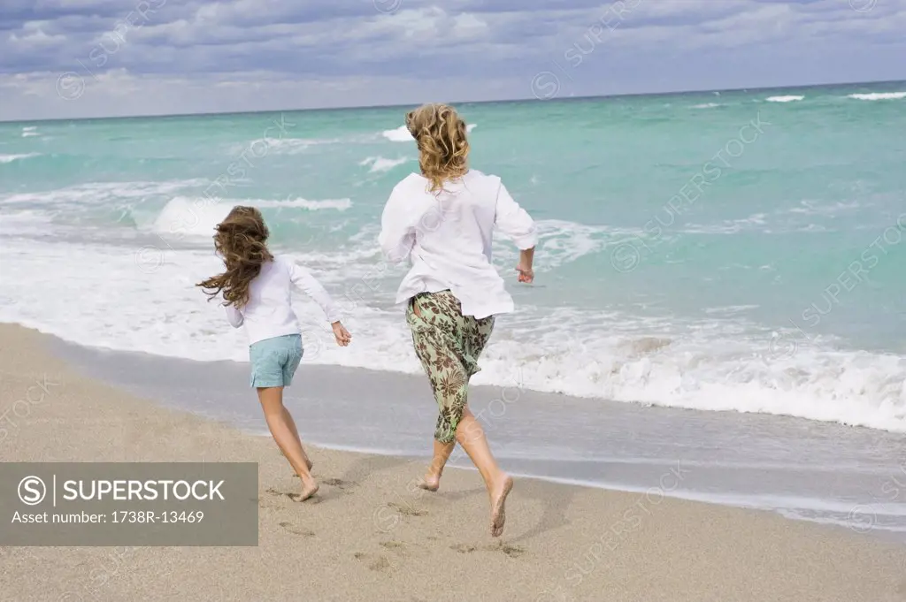 Woman running with her daughter on the beach