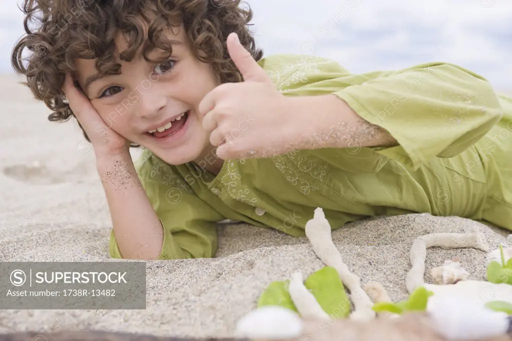 Boy showing thumbs up sign on the beach