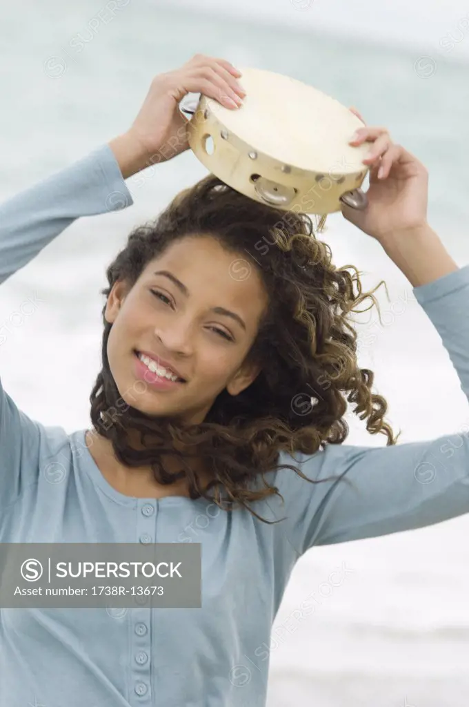 Portrait of a girl holding a tambourine over her head