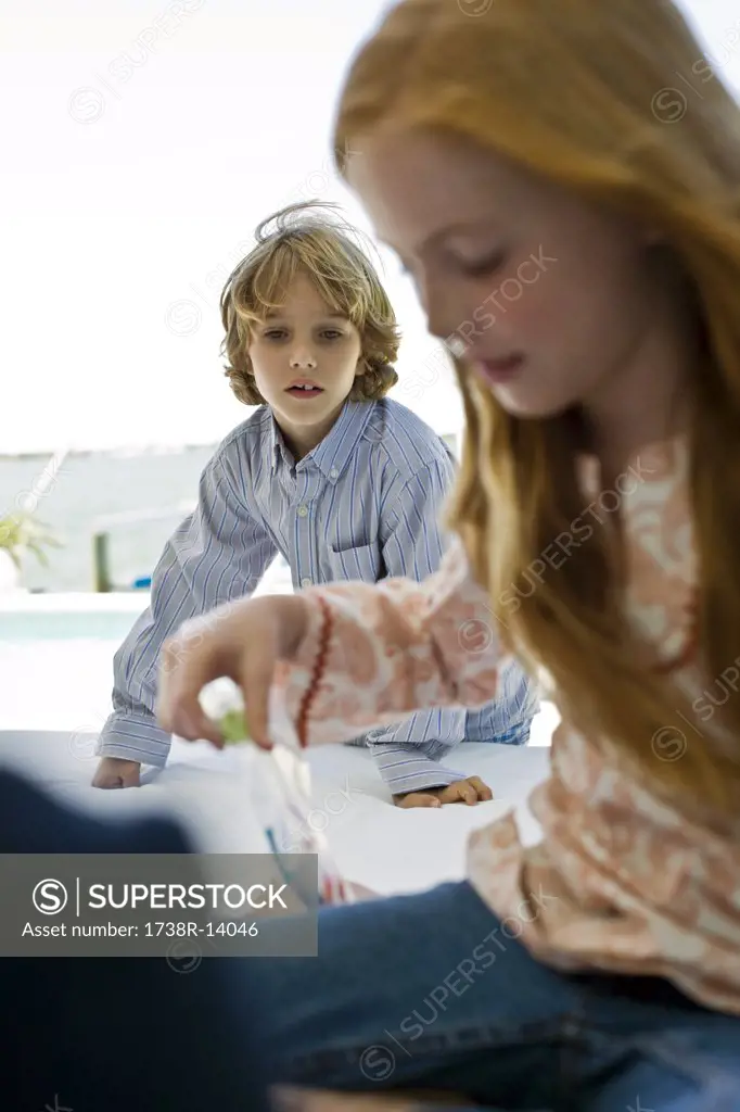 Girl playing with toys and a boy looking at her