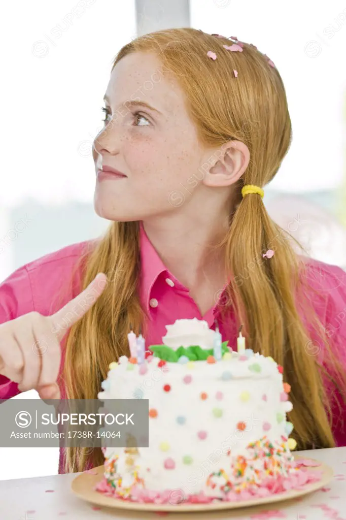 Girl pointing at a birthday cake
