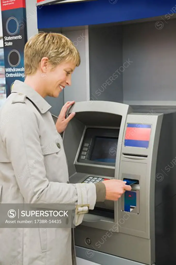 Woman inserting a credit card into ATM