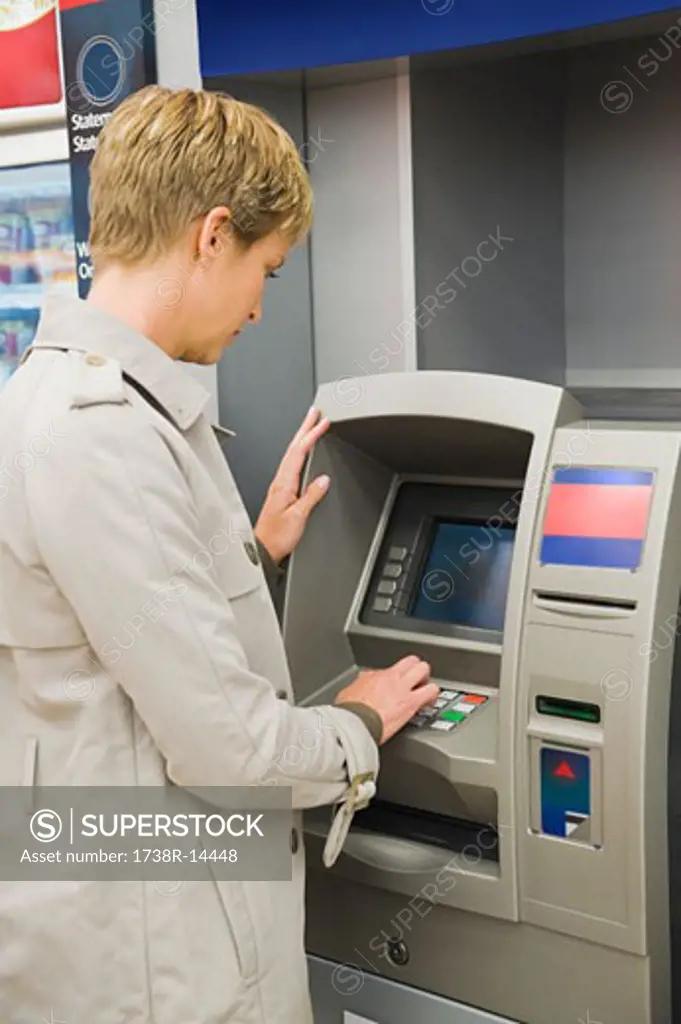 Woman entering pin number in an ATM