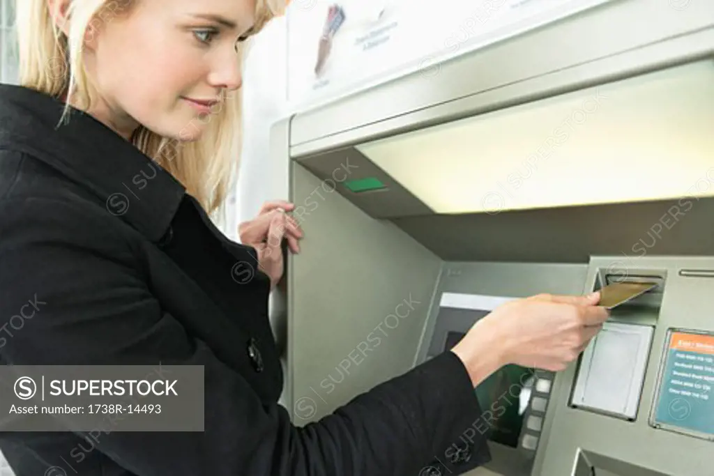 Woman inserting a credit card into ATM