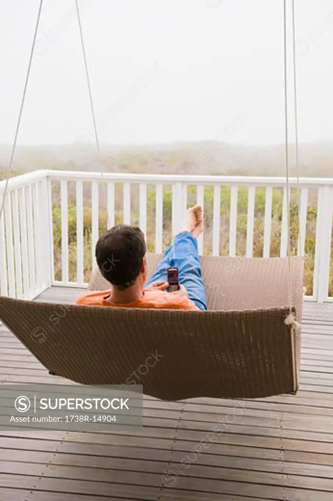 Man using a mobile phone on a porch swing