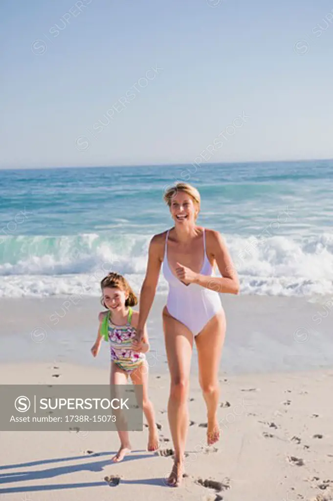 Woman running on the beach with her daughter