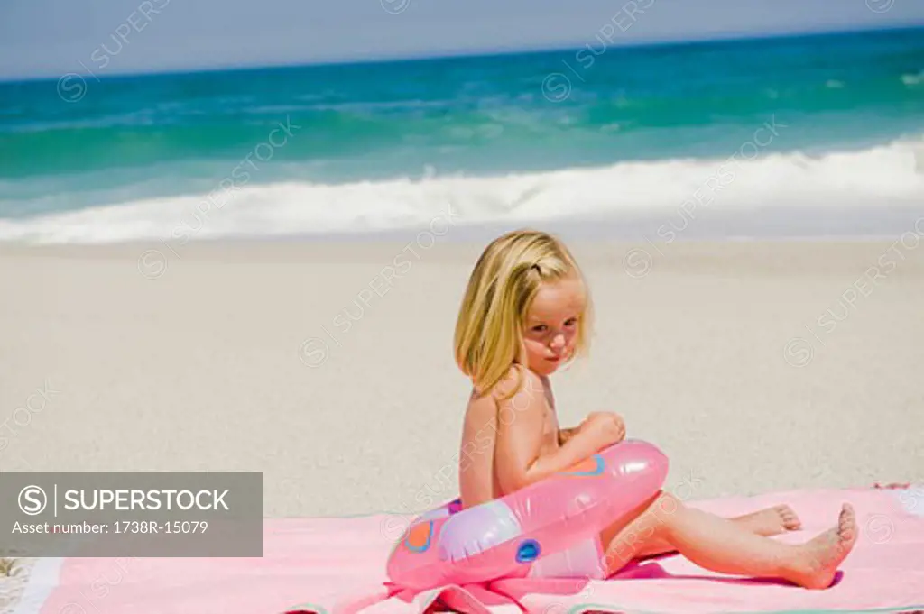 Girl sitting with an inflatable ring on the beach