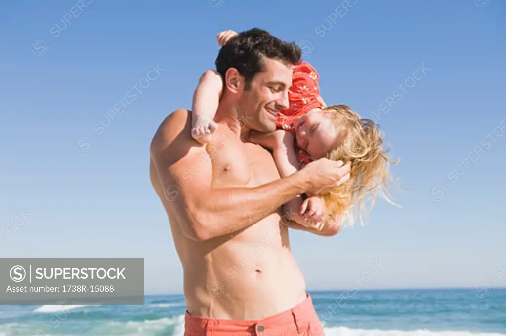 Man carrying his daughter on his shoulders on the beach