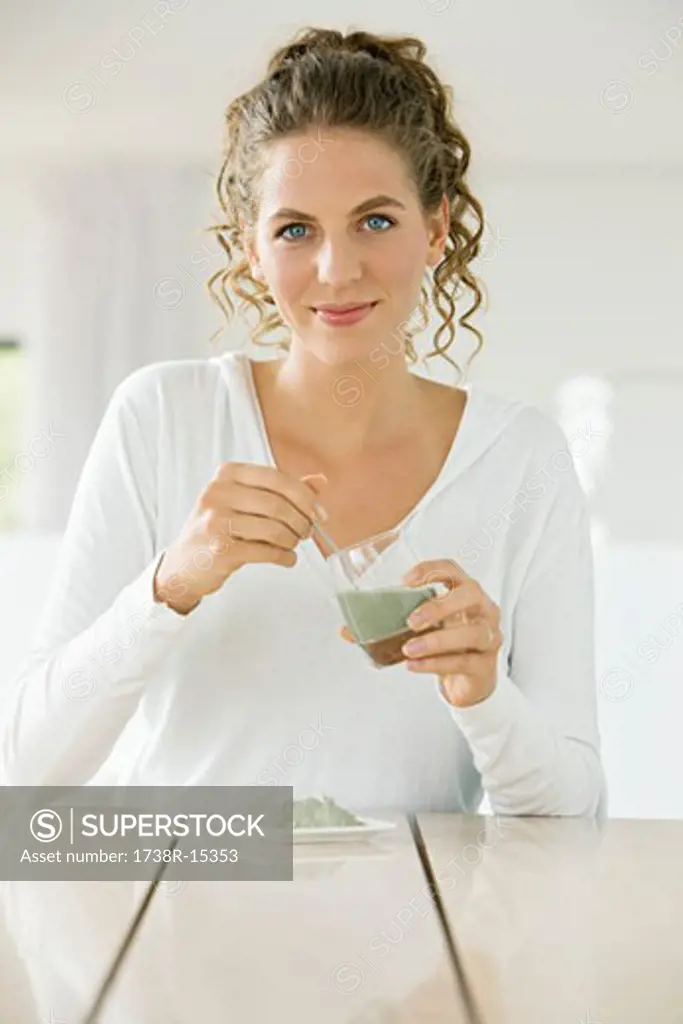 Portrait of a woman mixing green clay for facial mask