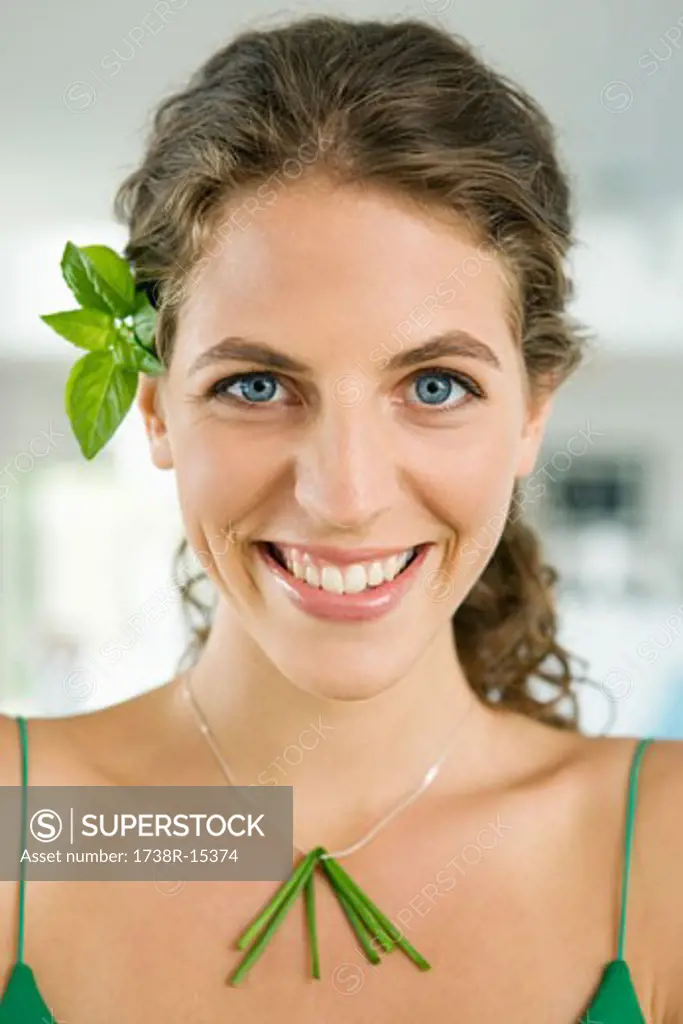 Woman smiling and wearing vegetable leaves in the kitchen