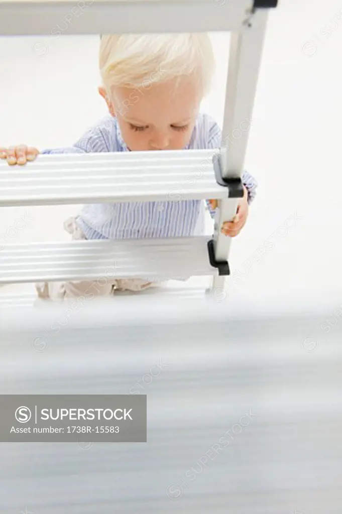Baby boy climbing a step ladder