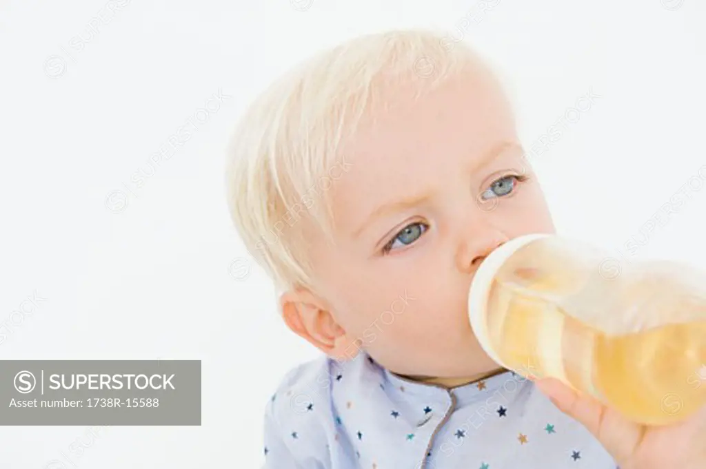 Baby boy drinking juice from a baby bottle