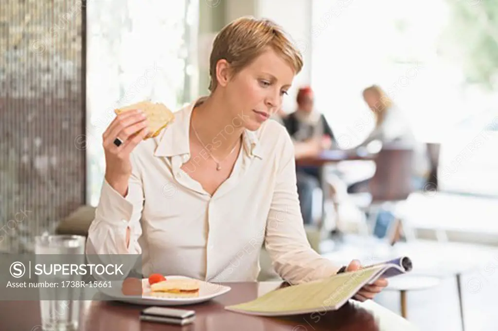 Businesswoman sitting in a restaurant and reading a magazine