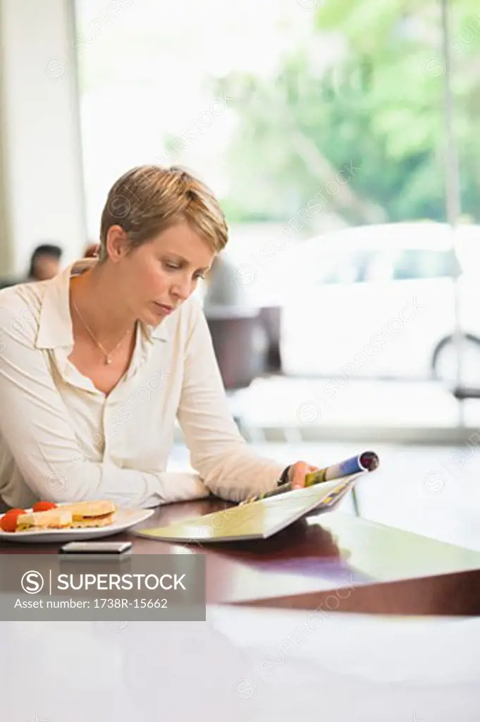Businesswoman sitting in a restaurant and reading a magazine
