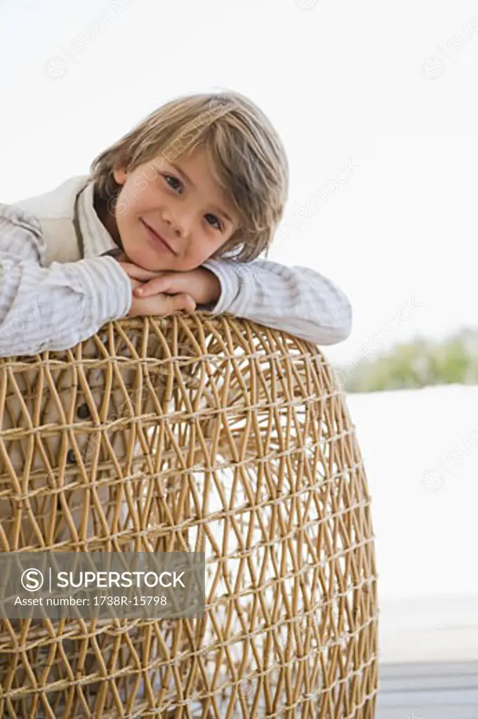 Portrait of a boy leaning on a wicker chair