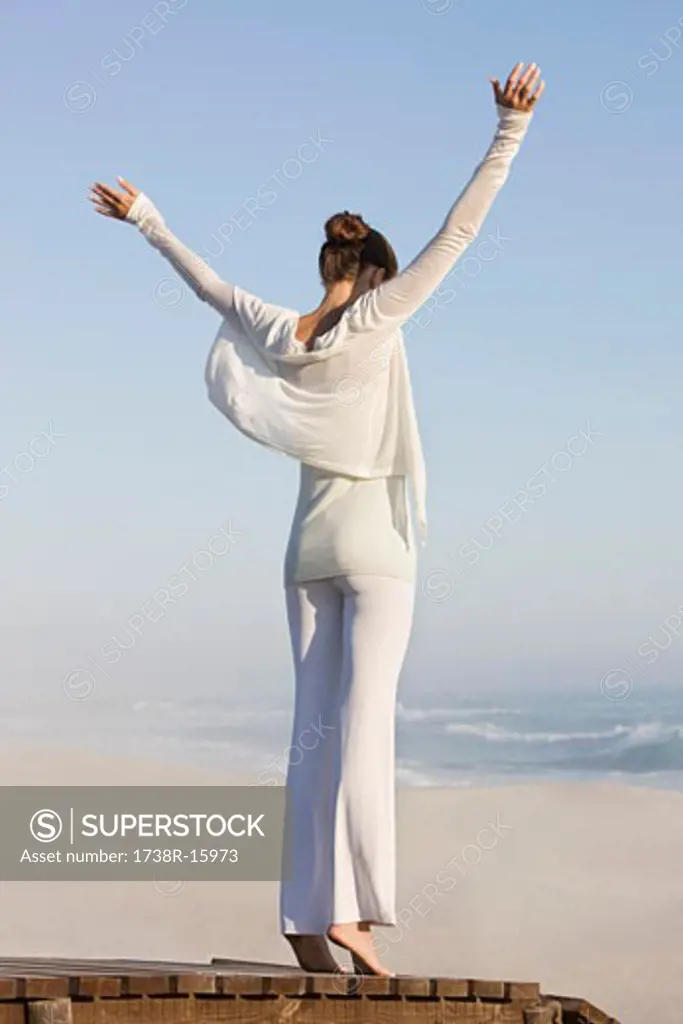 Woman standing on a boardwalk with her arms raised