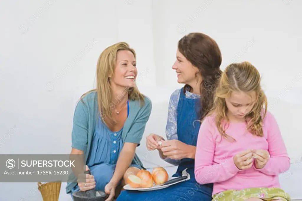 Two women preparing food with a girl at home