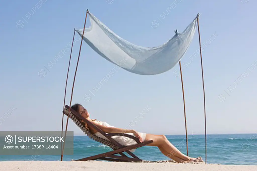 Woman resting in a deck chair under a canopy