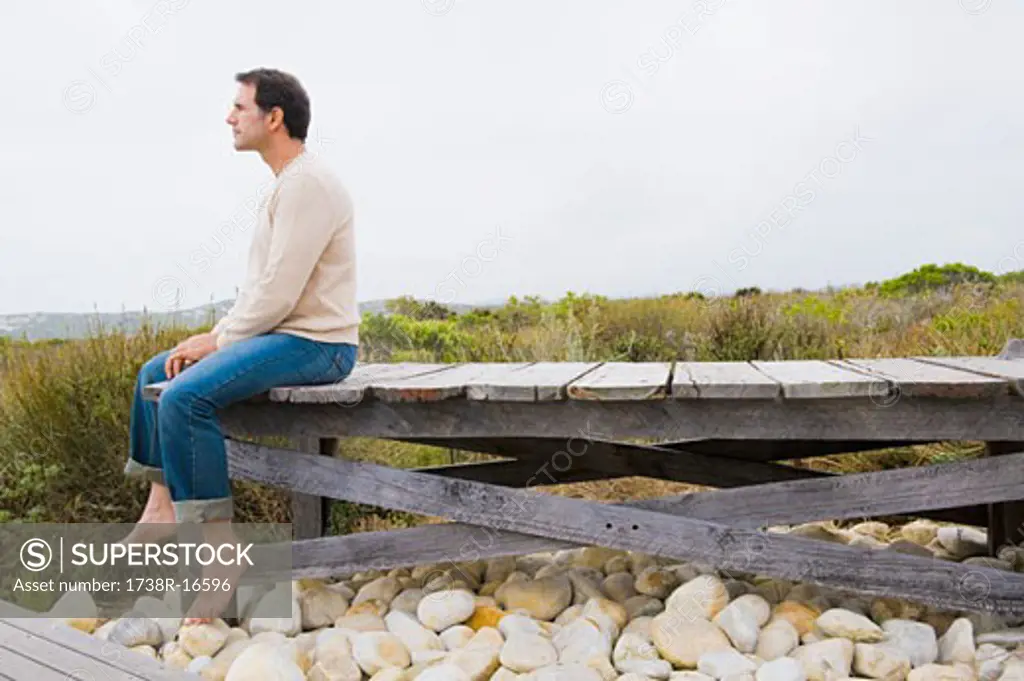 Man sitting on a boardwalk and thinking