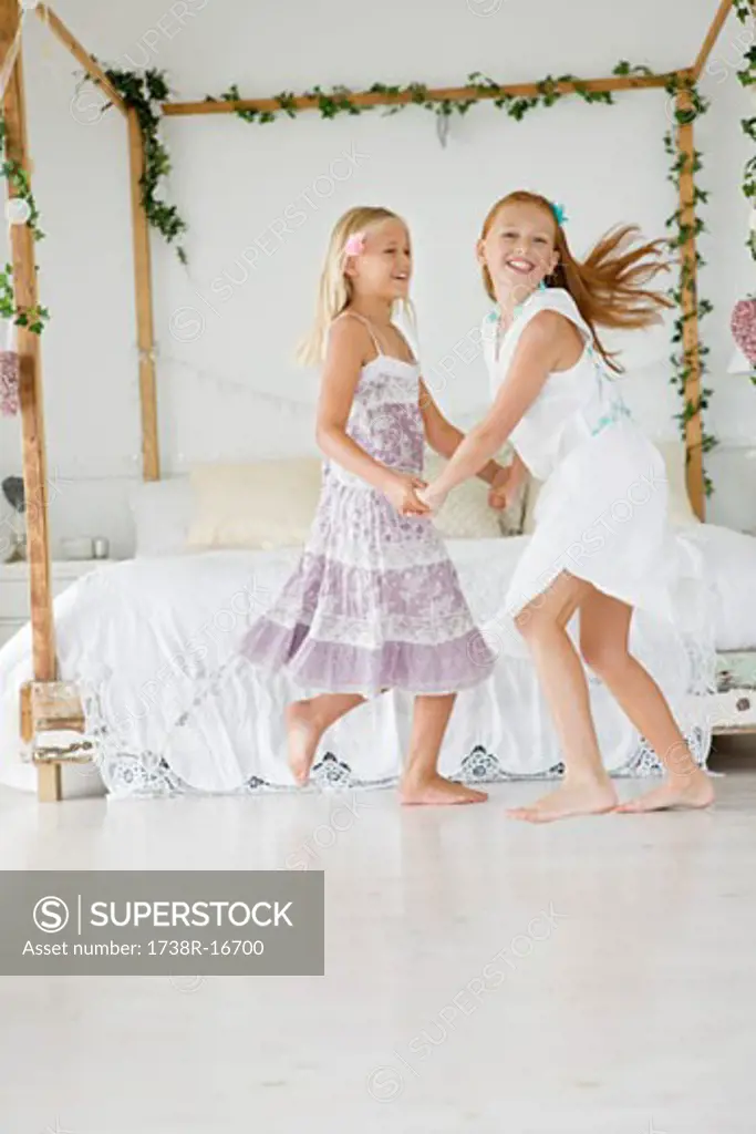 Two flower girls playing in a bedroom