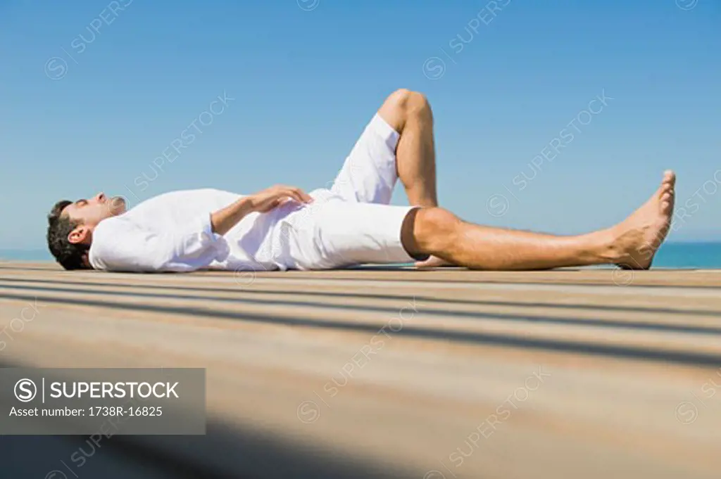 Man lying on a boardwalk on the beach