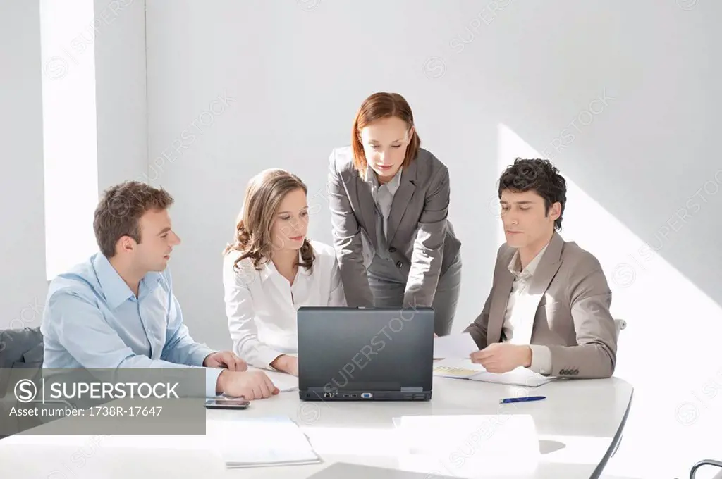 Business executives looking at a laptop in a board room