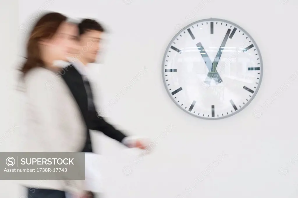 Business executives walking together in front of a wall clock