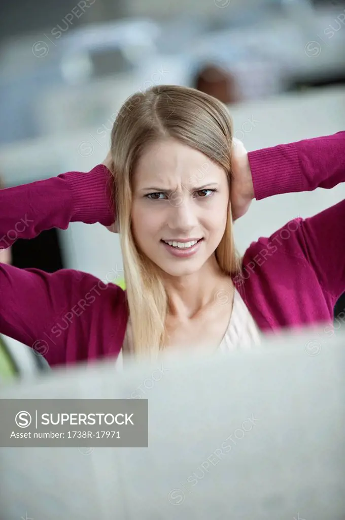 Businesswoman covering her ears in an office