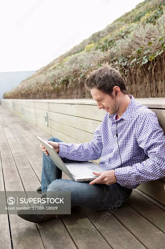 Man using a laptop and listening to music
