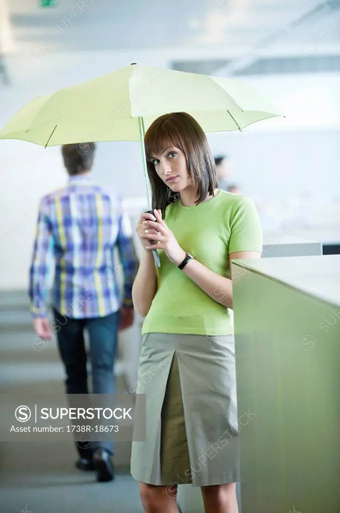 Businesswoman holding an umbrella in an office