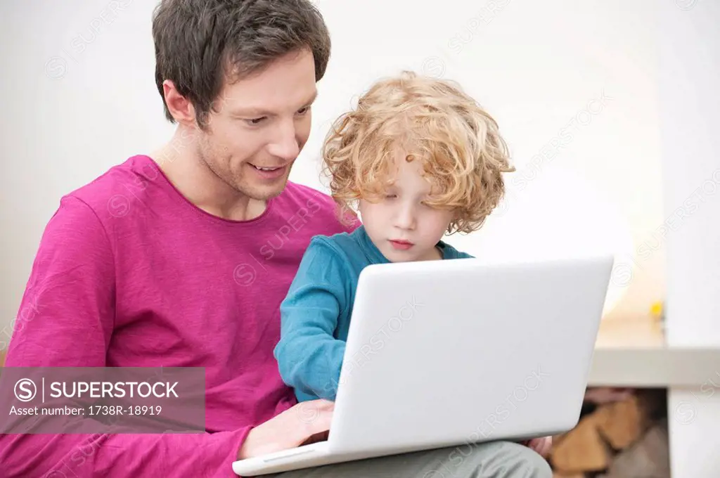 Close_up of a man assisting his son in using a laptop