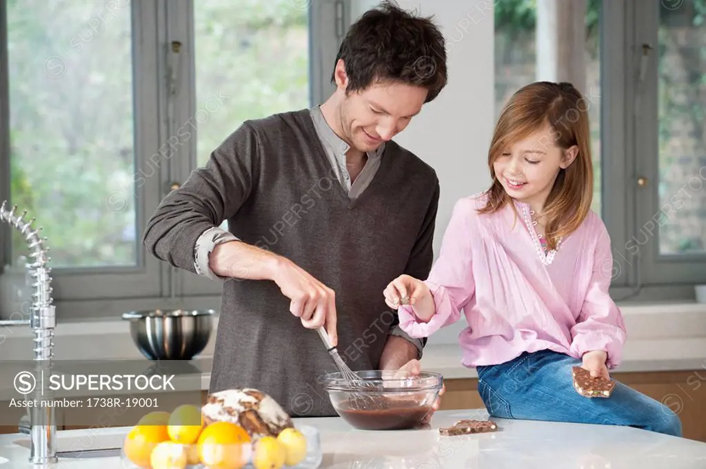 Man stirring a mixture in a bowl with his daughter