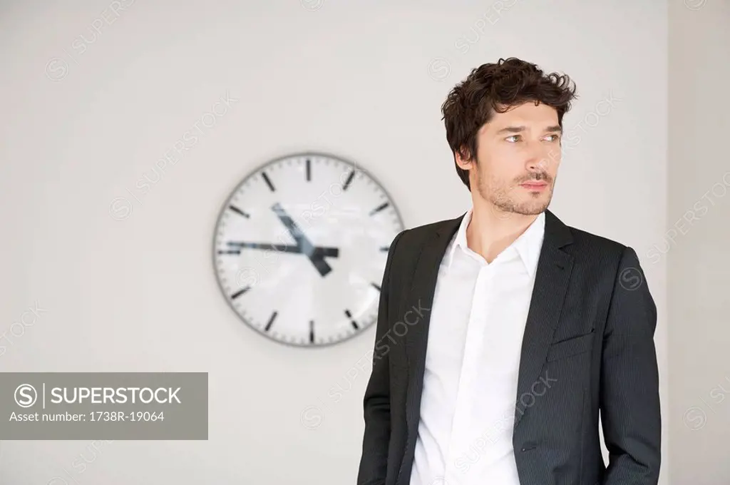 Businessman standing in front of a clock