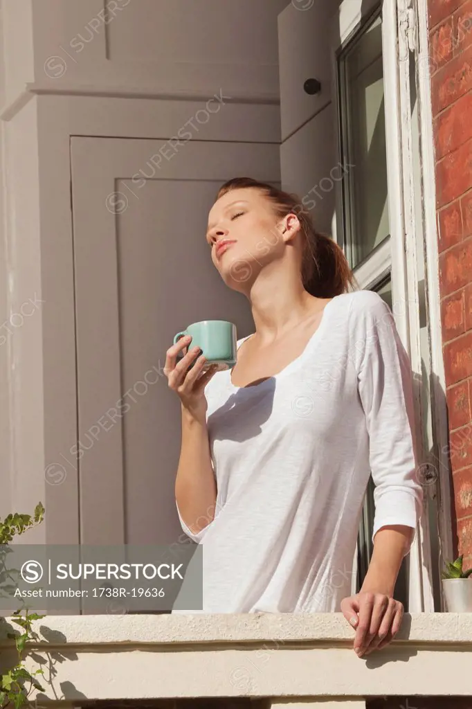 Young woman enjoying sun at window