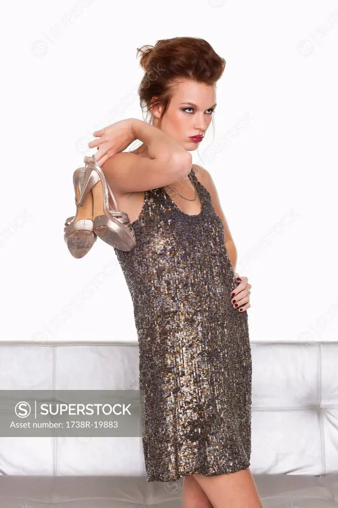 Young woman in formalwear holding shoes