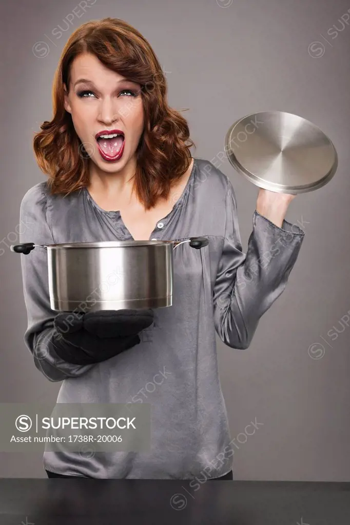 Young woman looking at content of stew pot