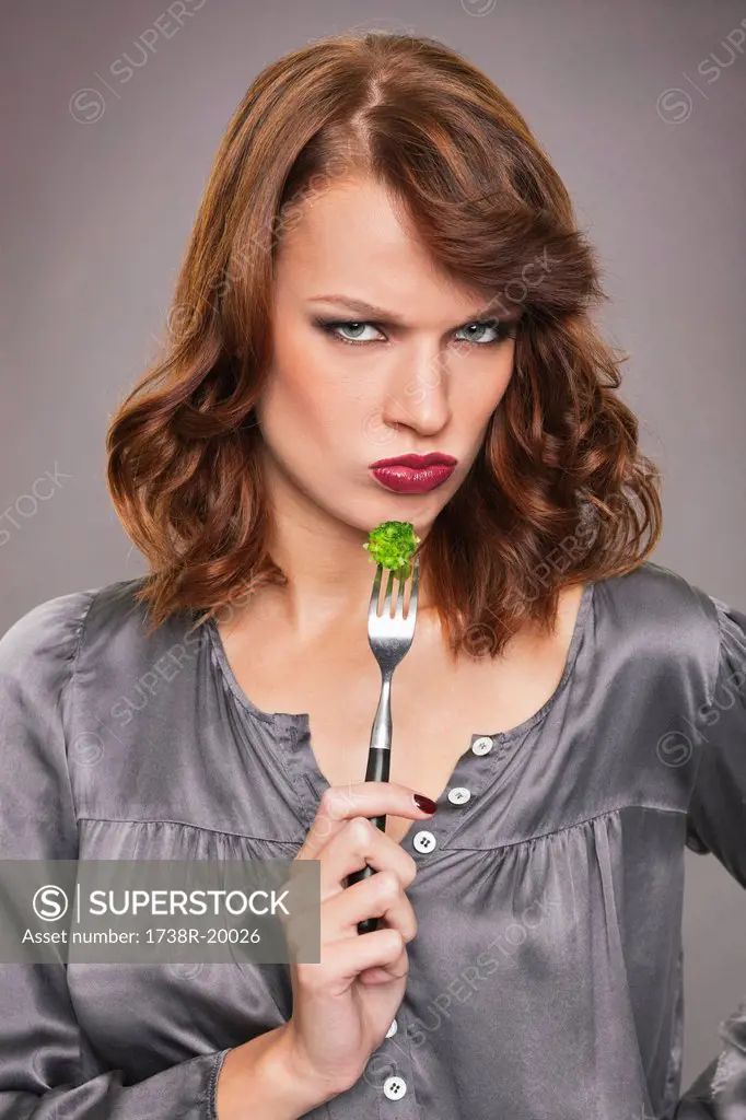 Young woman eating broccoli