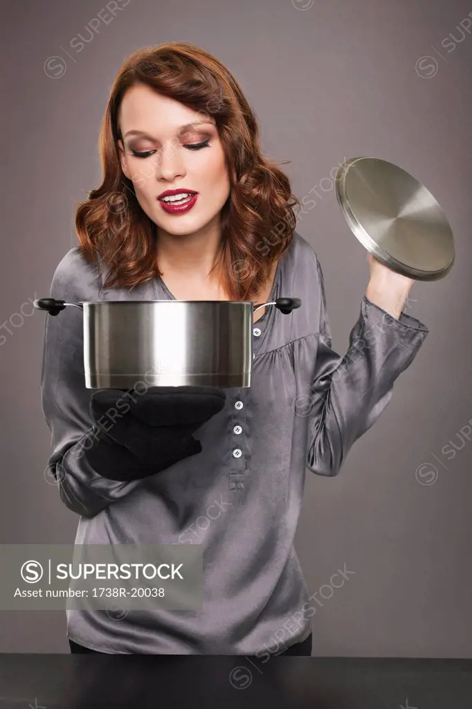Young woman looking at content of stew pot