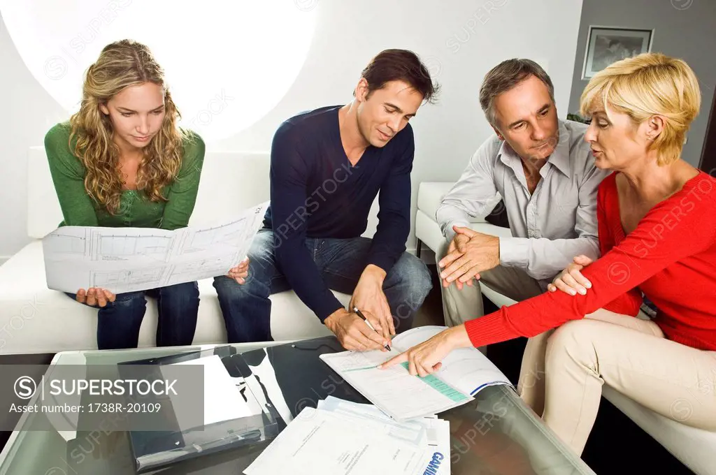 Young couple signing document with mature couple at home