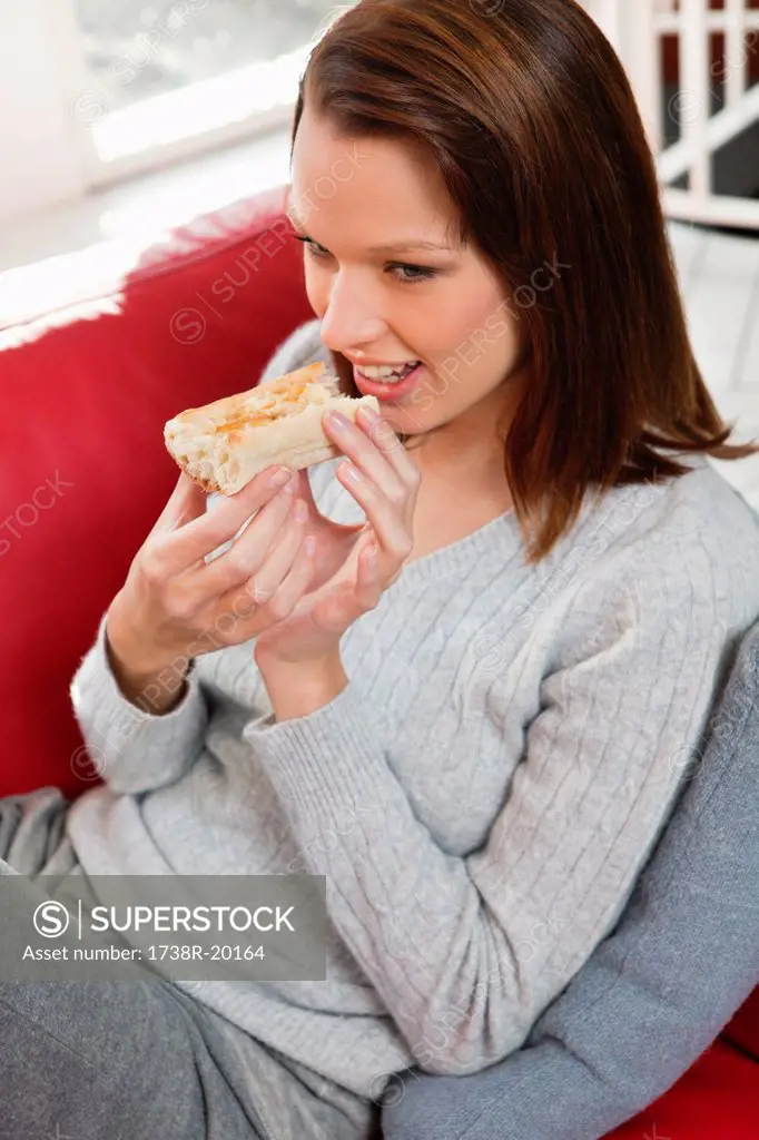 Young woman eating slice of bread