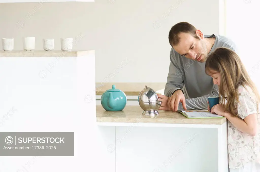 Father and daughter in kitchen, reading
