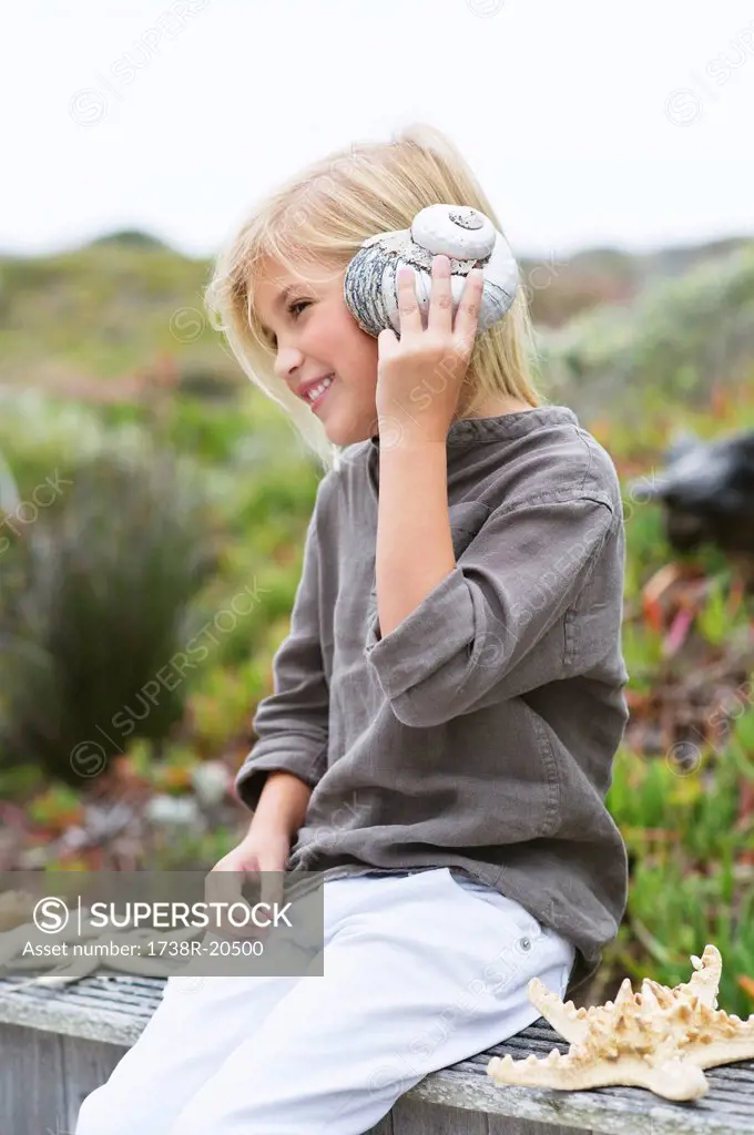 Girl listening to conch shell and smiling