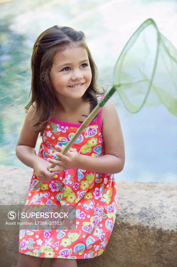 Little girl sitting by the swimming pool with net in hand