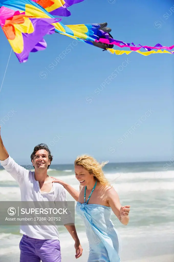 Mid adult couple flying kite on the beach
