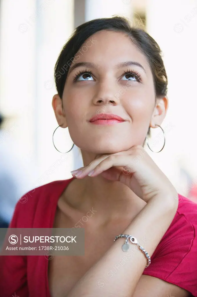 Smiling woman looking up with hand on chin