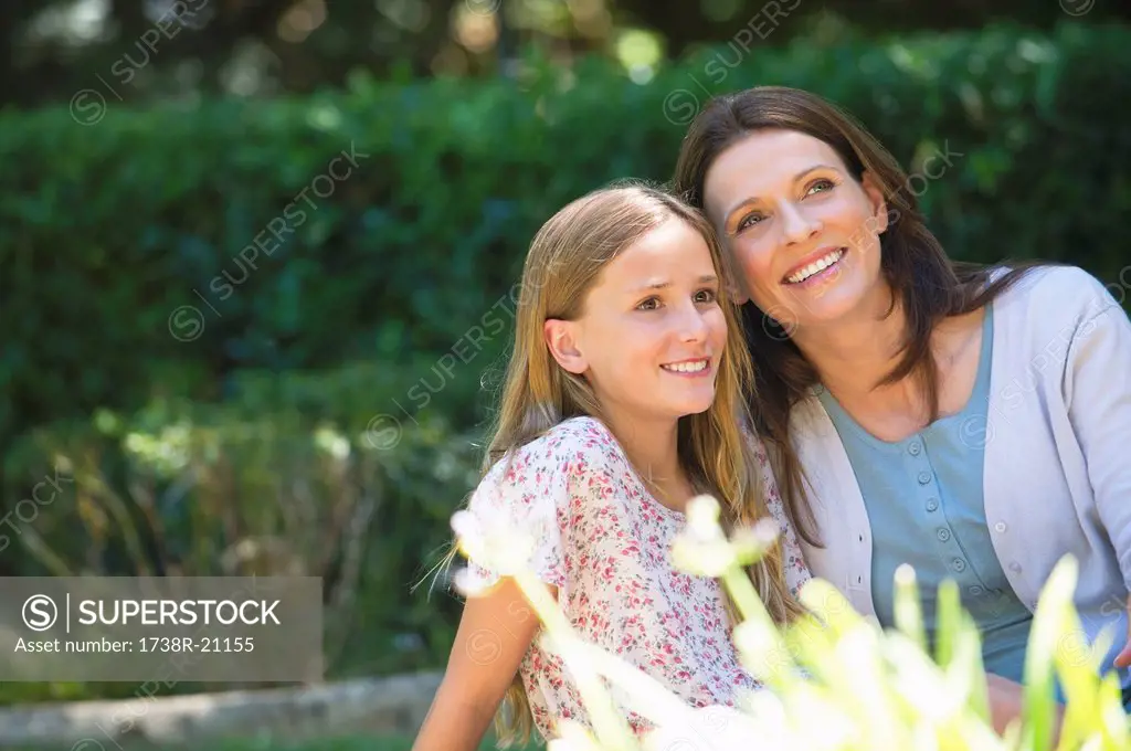 Cute little girl and her mother sitting together in the garden