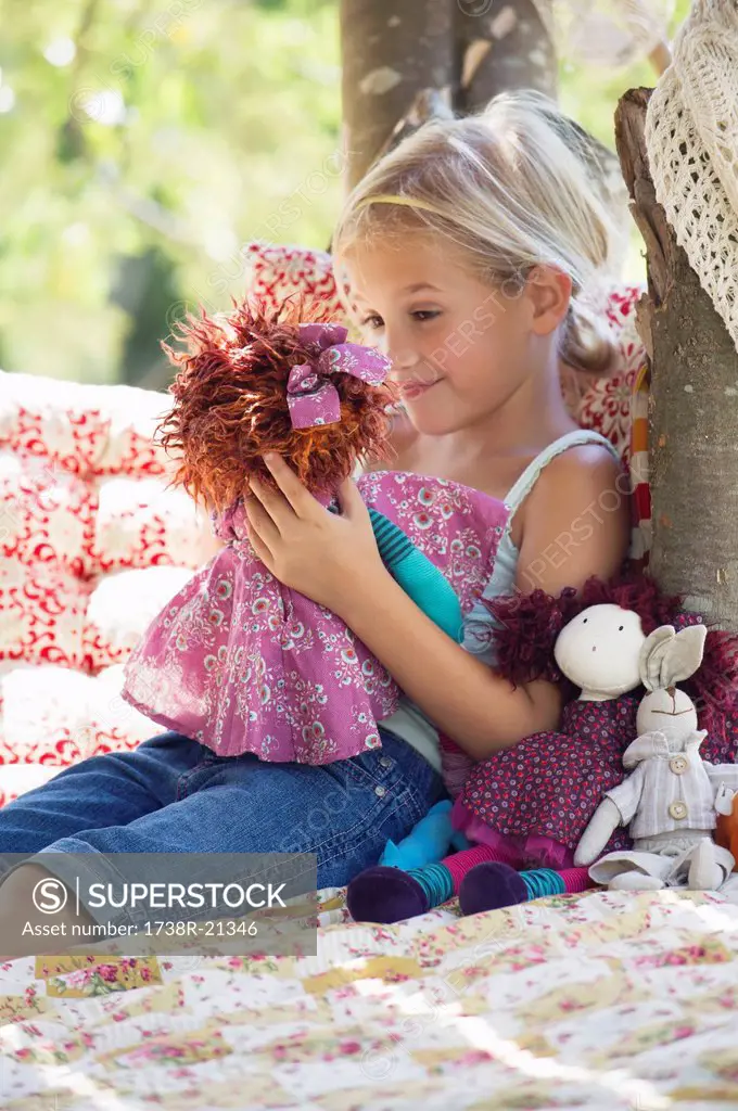 Smiling little girl holding toys in tree house